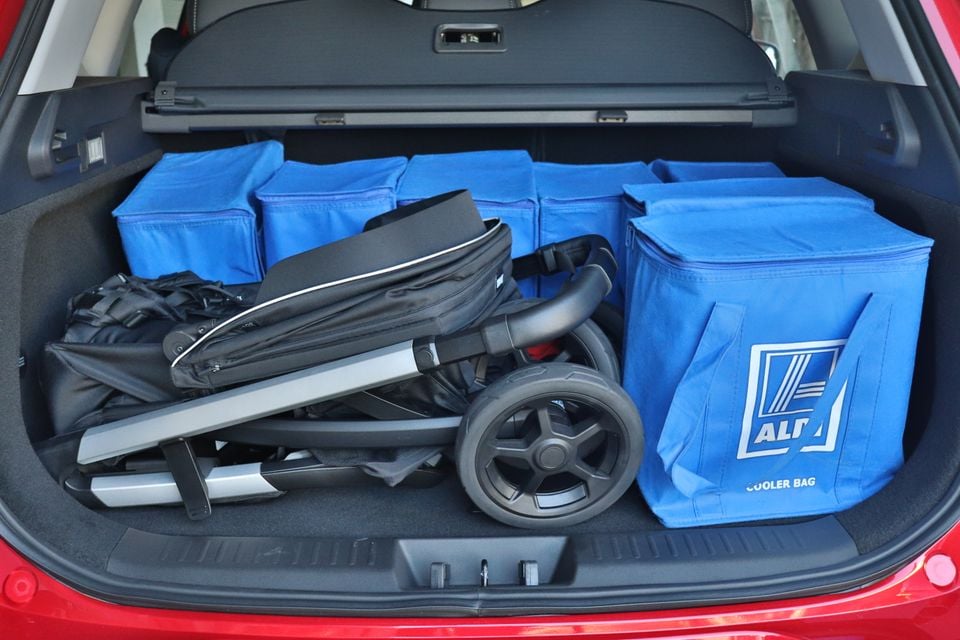 The boot of a red 2026 Chery Tiggo 7 SUV packed with Aldi cooler bags and a folded pram.