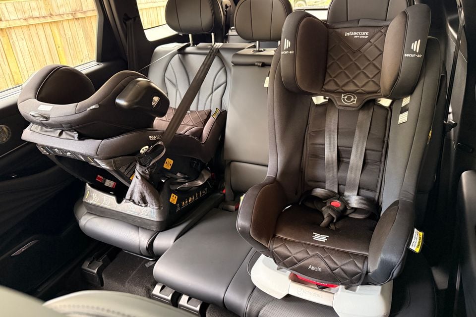 Two child car seats, an infant capsule and a booster seat, installed in the second row of a vehicle's rear seats