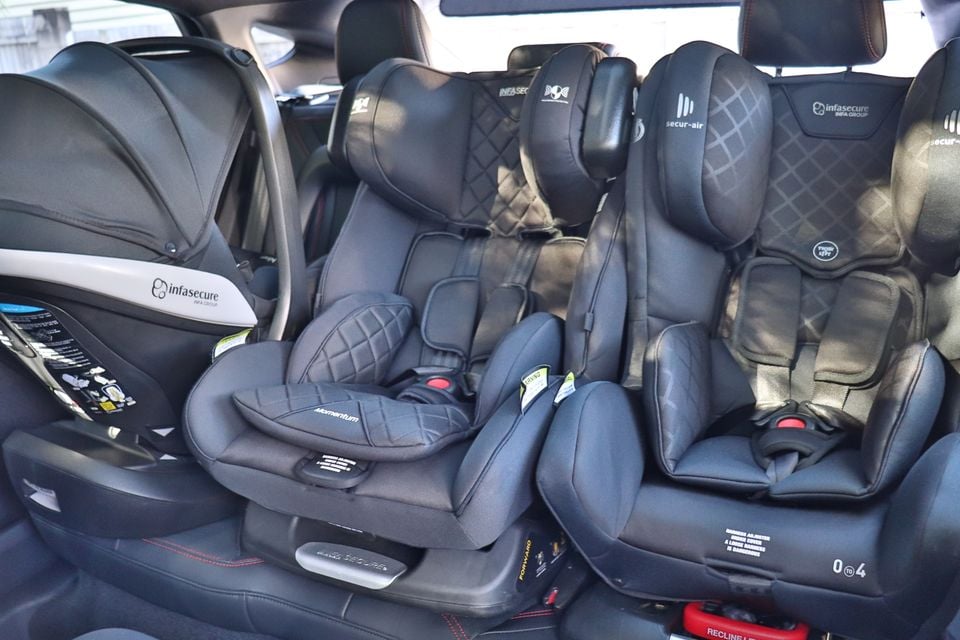 Three Infasecure child car seats installed across the rear seat of a car, including a rear-facing infant capsule on the left and two forward-facing seats