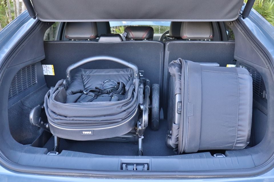 Boot of a 2026 Ford Mustang Mach-E open and loaded with a folded Thule pram and a large suitcase