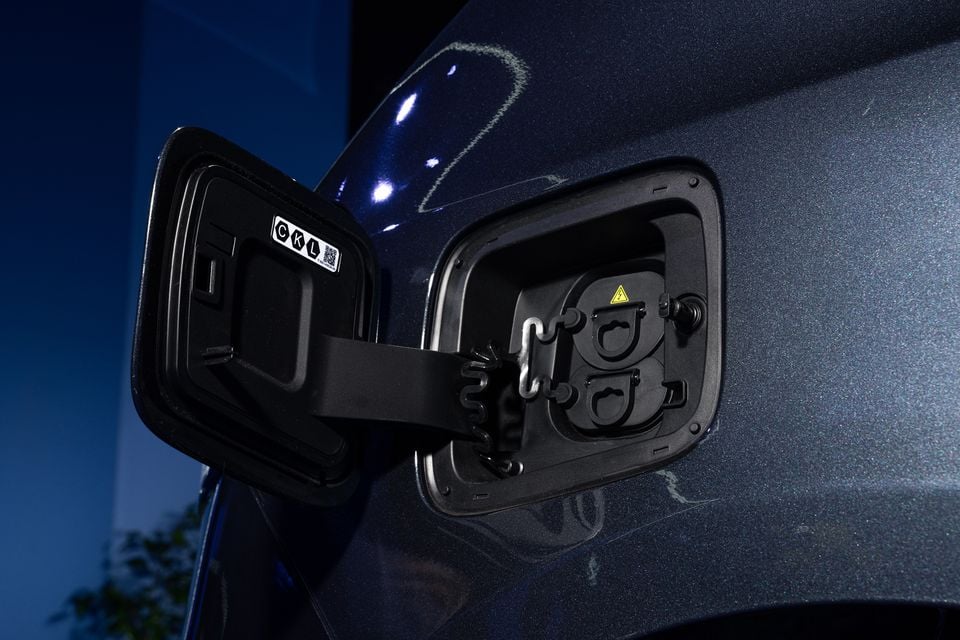 Close-up of the open charging port on a dark blue 2026 Ford Transit City, showing a CCS charging socket with a high-voltage warning label