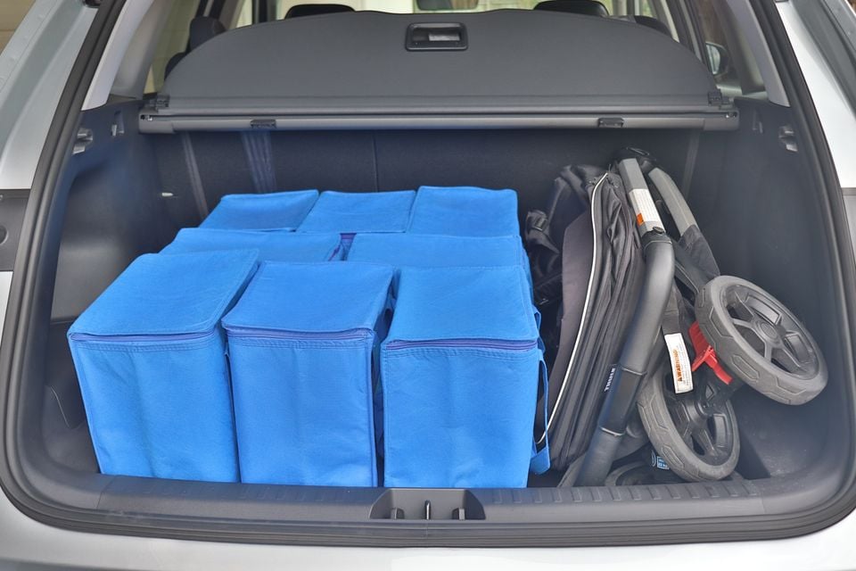 The boot of a 2026 Geely Starray loaded with blue storage boxes and a folded pram or stroller.