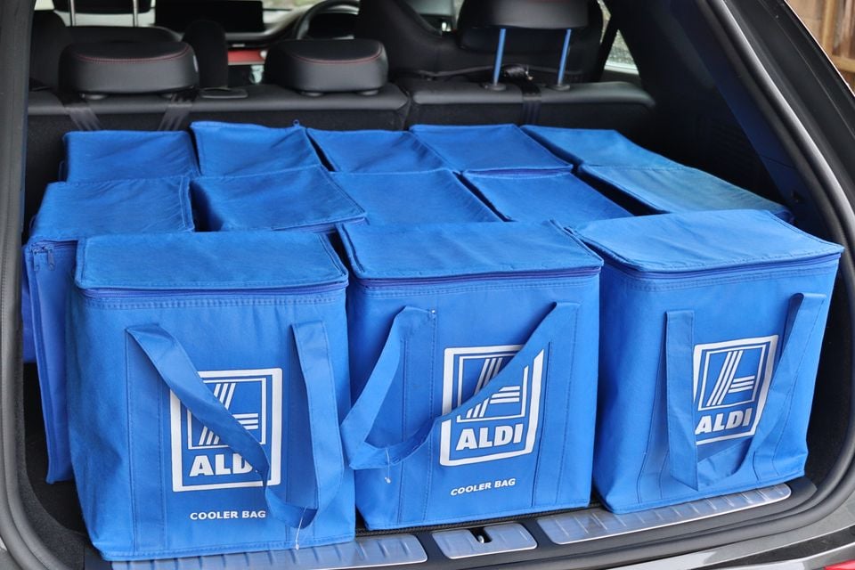 Multiple blue Aldi cooler bags filling the boot of an SUV, with rear seats visible in the background