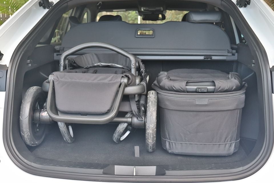 Boot of a white 2026 Haval H6 GT holding a folded black pram and a Thule carry bag, with the cargo cover in place