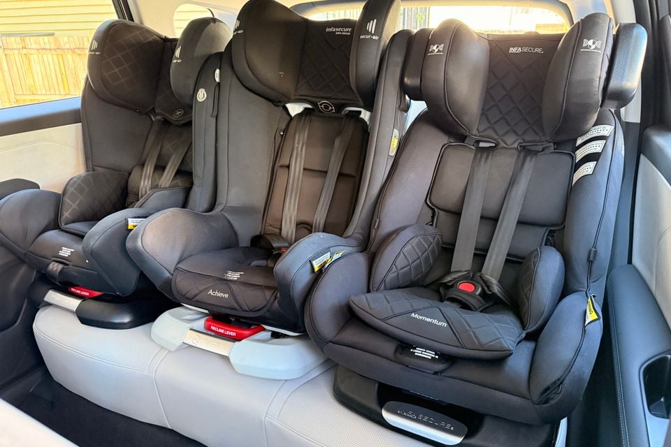 Three Infasecure child car seats fitted side by side across the rear seat of a vehicle, including the Achieve and Momentum models