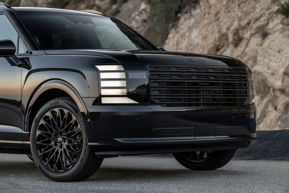 A black 2026 Hyundai Palisade SUV seen from the front-side angle, showing its bold grille, distinctive headlights, and dark alloy wheels against a rocky backdrop.