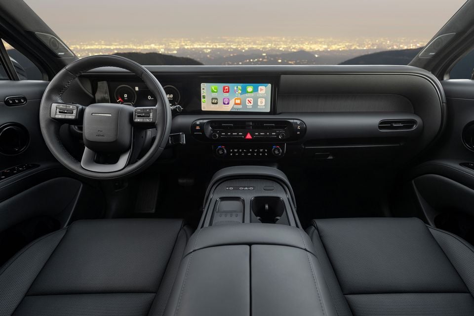 Interior of the 2026 Hyundai Palisade showing the dashboard, steering wheel, wide infotainment touchscreen displaying Apple CarPlay, climate controls, and dark leather front seats