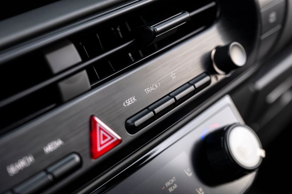 Close-up of the centre console controls in a 2026 Hyundai Palisade, showing seek and track audio buttons, hazard light button, and climate control knobs