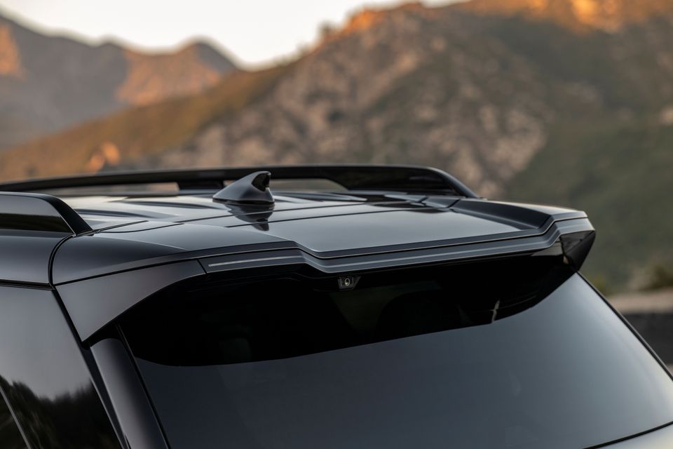 Close-up of the roof spoiler and shark fin antenna on a dark 2026 Hyundai Palisade, with rocky mountains in the background
