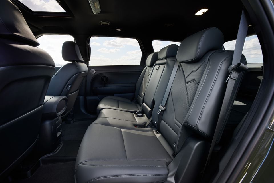 The rear seats of a 2026 Hyundai Palisade XRT Pro SUV, showing a dark leather three-seat bench with seatbelts, a panoramic sunroof overhead, and large side windows.