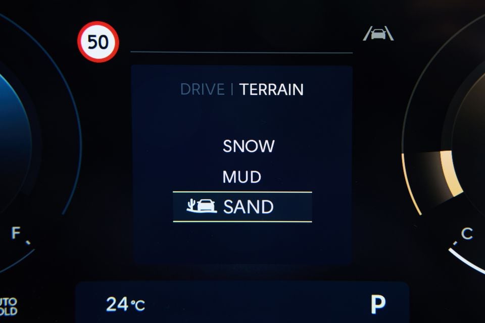 A car instrument cluster display showing the Drive Terrain menu with Sand mode selected, alongside Snow and Mud options