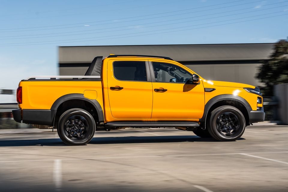 A yellow JAC Hunter PHEV dual-cab ute seen from the side while driving on a road