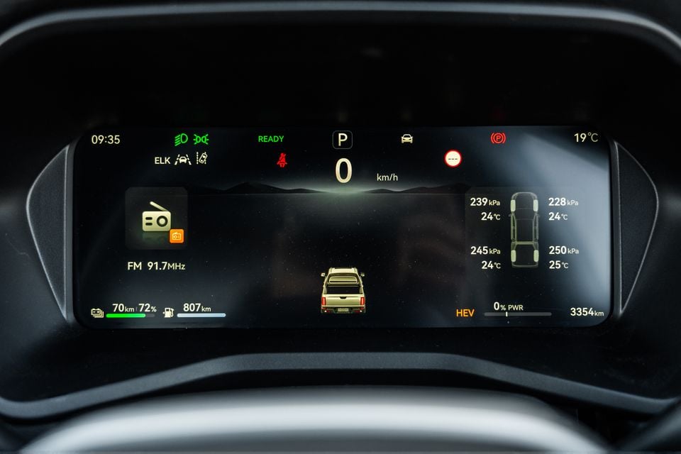 Digital instrument cluster of a 2026 JAC Hunter PHEV showing speed, HEV status, tyre pressure readings, FM radio, and battery and fuel range information.