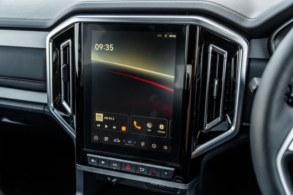 The vertical touchscreen infotainment display inside a 2026 JAC Hunter PHEV, showing FM radio, phone, and climate controls on the centre console