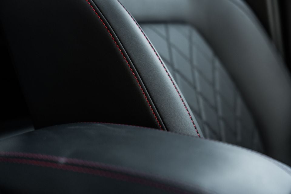 Close-up of black leather car seat with red contrast stitching and diamond-pattern quilting in a JAC Hunter PHEV