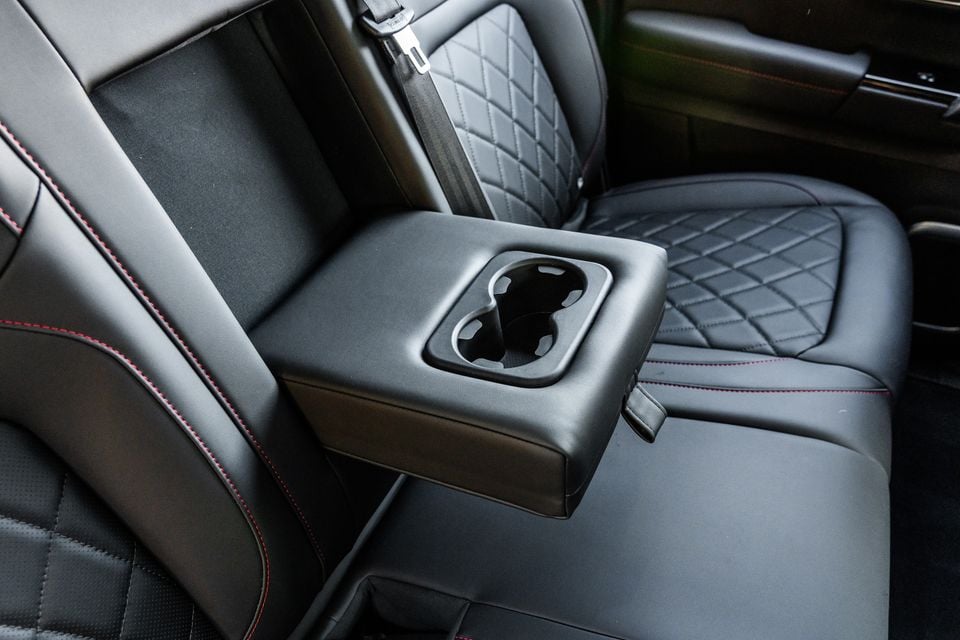 Rear centre armrest with dual cup holders in a JAC Hunter PHEV, featuring black leather seats with diamond quilting and red contrast stitching