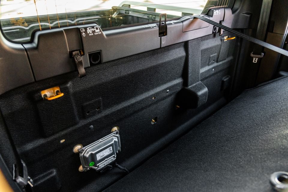 The cargo area of a JAC Hunter PHEV with the rear seats folded, showing a flat load floor with an exposed electronic control module mounted to the floor