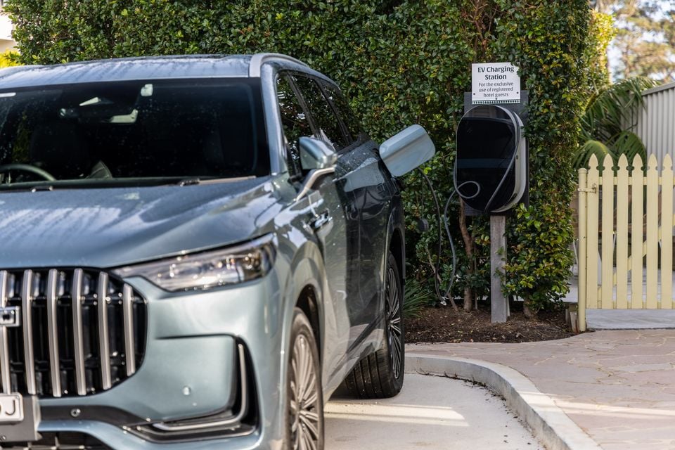 A grey 2026 Jaecoo J8 SUV plugged into an EV charging station at a hotel car park