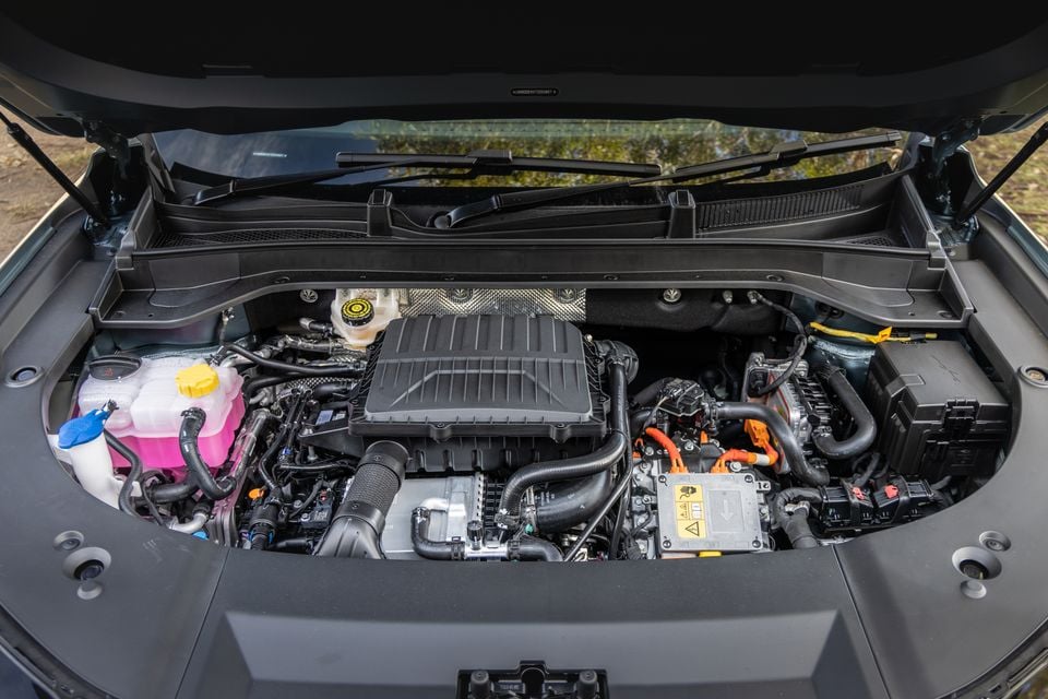 Engine bay of a 2026 Jaecoo J8 SHS hybrid, showing the petrol engine alongside orange high-voltage hybrid components and fluid reservoirs with the bonnet open.