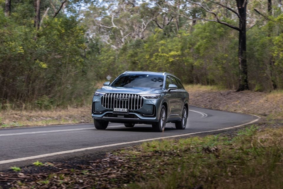 A silver 2026 Jaecoo J8 SUV driving along a winding road surrounded by Australian bush