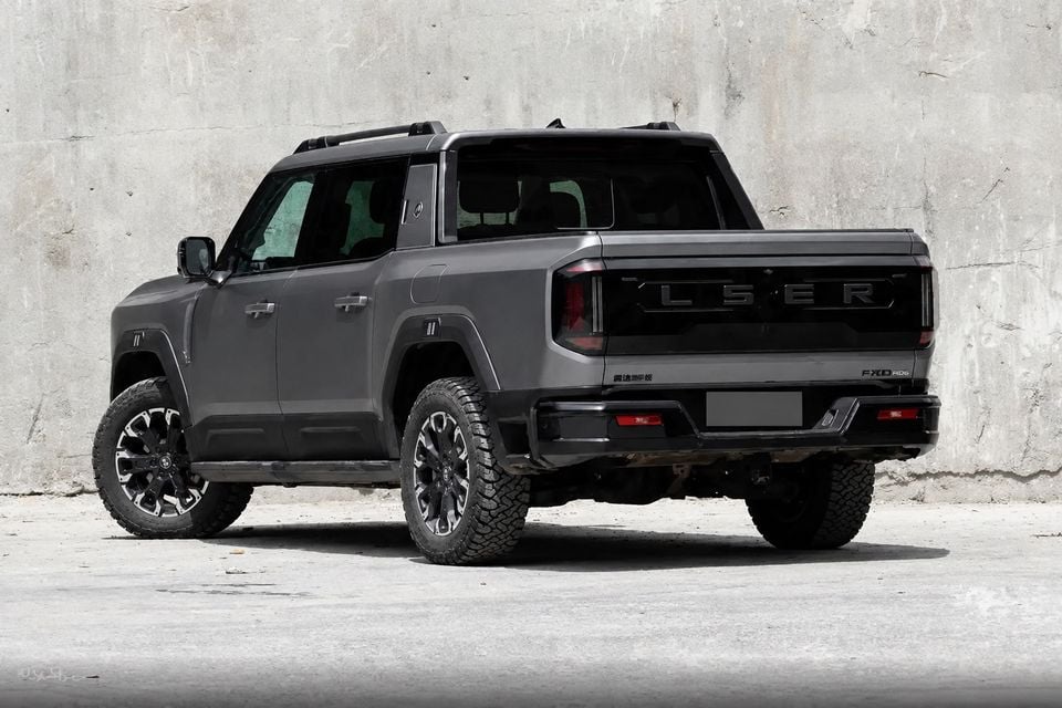 A dark grey Jetour F700 dual-cab ute seen from the rear three-quarter angle, parked against a concrete wall