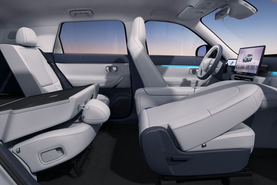 Interior of the 2026 Leapmotor B03X showing light grey and navy two-tone seats, a large touchscreen infotainment display, steering wheel, and ambient lighting strip across the cabin.
