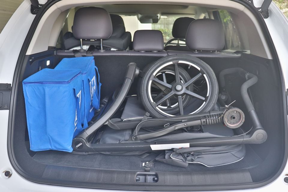 The boot of a white 2026 Leapmotor C10 SUV loaded with a folded Thule pram and blue insulated shopping bags, seen through the open tailgate