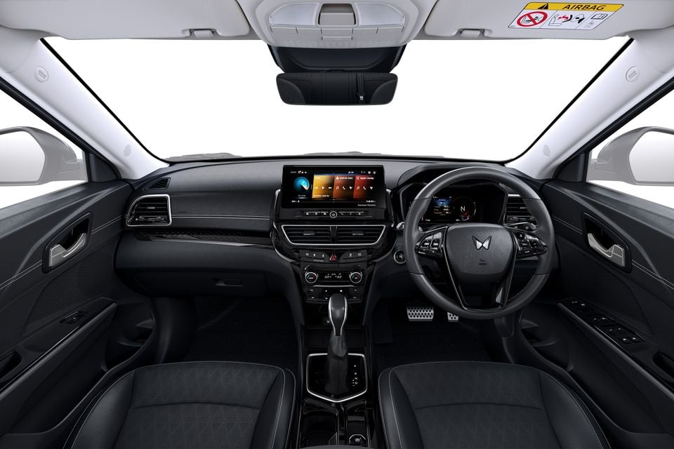 Interior view of a Mahindra XUV3XO showing the dashboard, touchscreen infotainment system, steering wheel, and front seats