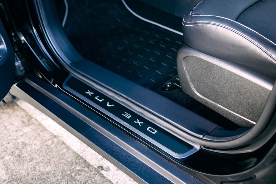 Door sill of the Mahindra XUV 3XO Black Edition with illuminated model name badging, with floor mat and seat visible inside