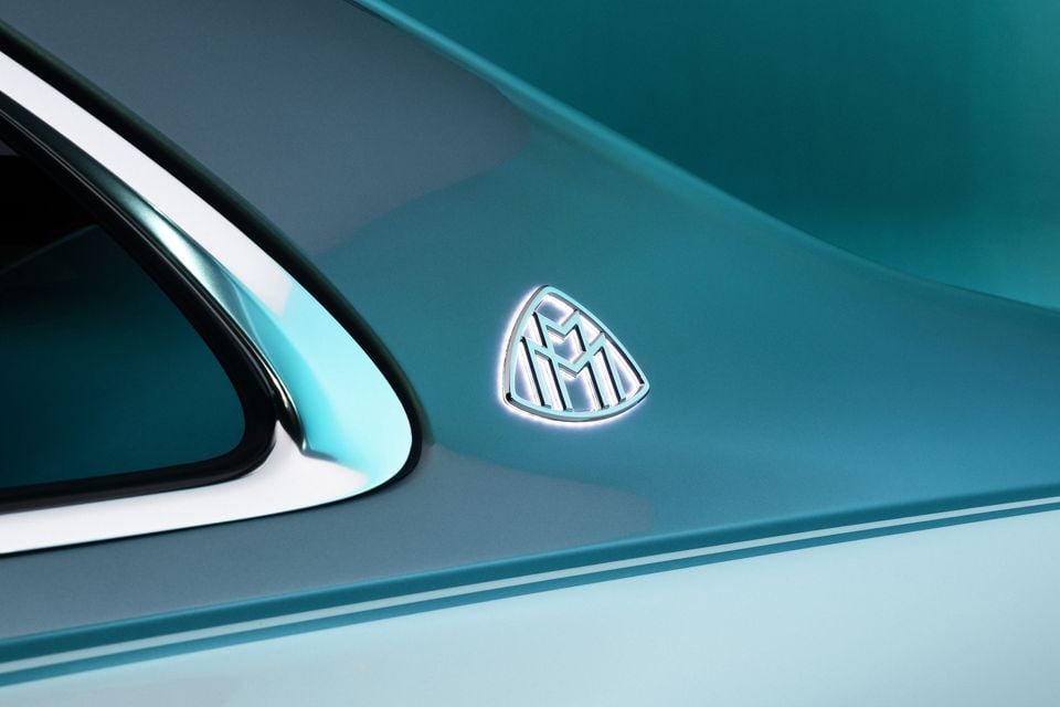 Close-up of the illuminated Mercedes-Maybach badge on the rear quarter panel of a teal 2026 Mercedes-Maybach