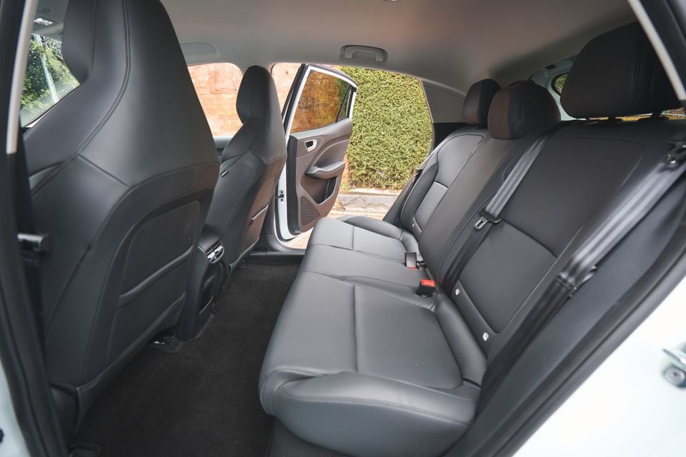 The black leather rear seats of a 2026 MG4 EV hatchback, viewed through the open door with seatbelts and headrests visible