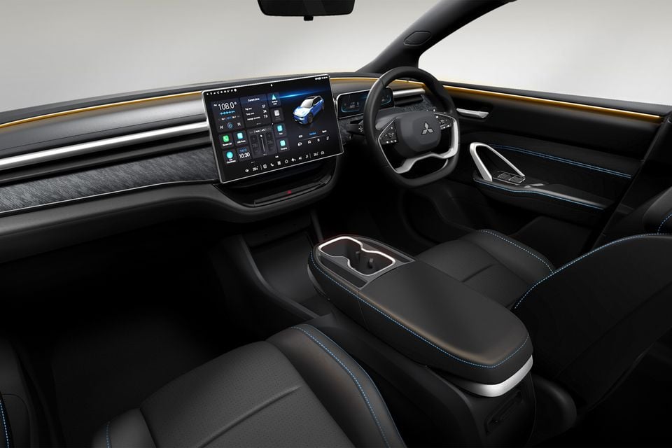 Interior of a 2026 Mitsubishi ASX showing the large central touchscreen infotainment display, steering wheel, centre console, and black leather seats with blue stitching