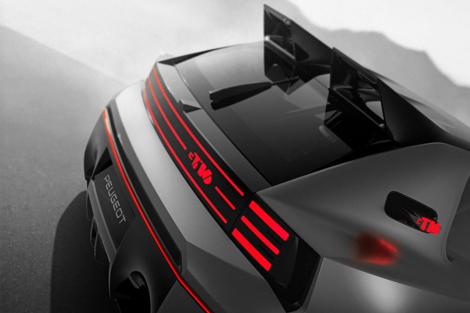 Rear of the grey 2026 Peugeot E-T16 concept seen from above, showing its red light bar, illuminated tail-lights and large rear wing