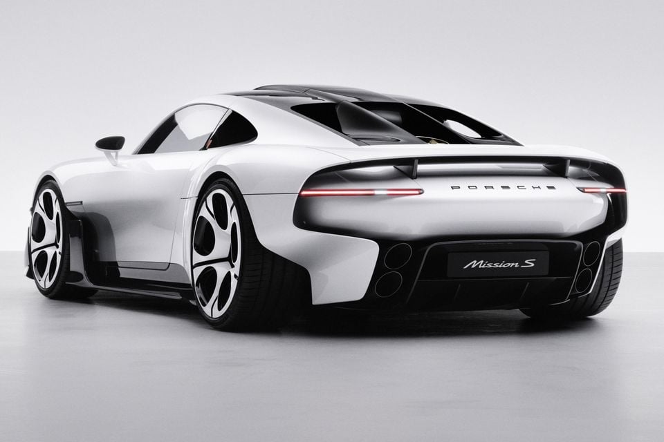 White Porsche Mission concept sports coupe seen from the rear three-quarter angle in a studio, showing its full-width tail-lights and large wheels