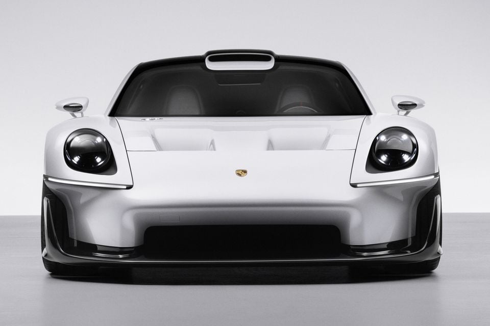 A white 2026 Porsche Mission E-inspired supercar concept seen from the front in a grey studio, showing round headlights and a roof scoop