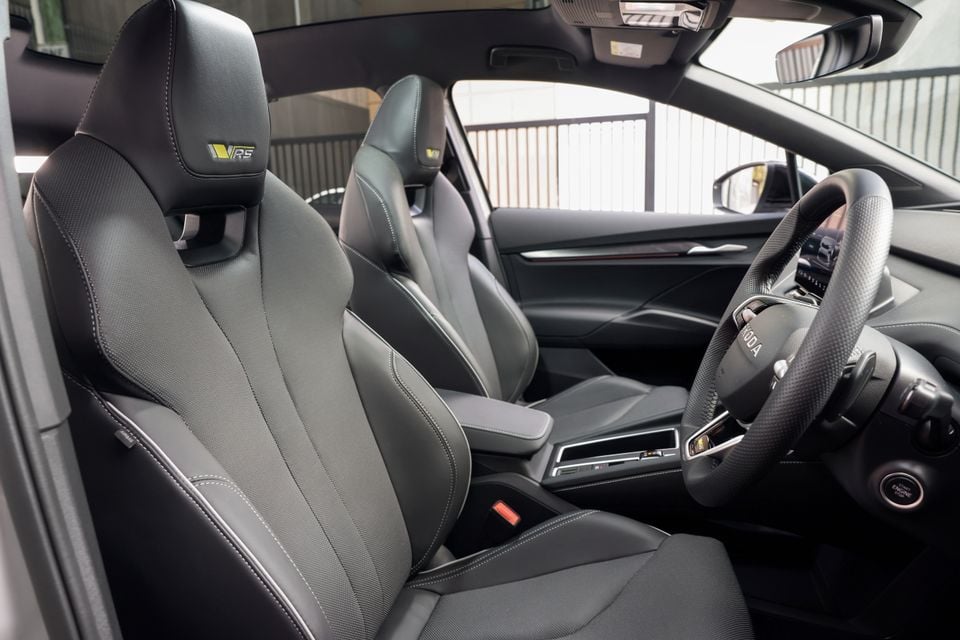 Interior of a Skoda Enyaq vRS showing black sport seats with vRS-branded headrests, centre console, and the Skoda steering wheel
