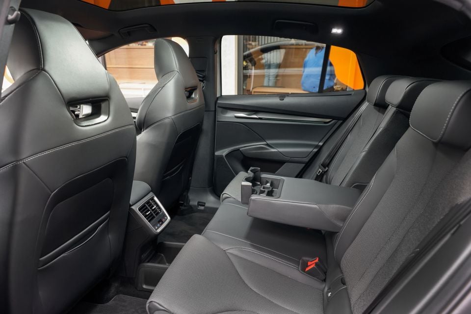 Rear interior of a 2026 Skoda Enyaq showing the back seats with a centre armrest, cup holders, rear air vents, and dark upholstery