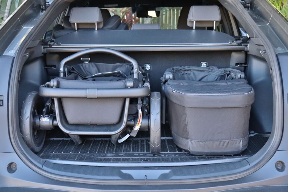 The boot of a 2026 Subaru Solterra SUV loaded with a folded pram and a large bag, viewed from the rear with the tailgate open