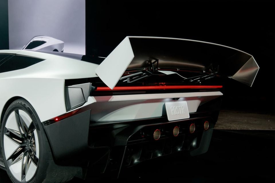 A white 2026 Tesla Roadster seen from the rear quarter with its active rear wing raised and an RDSTR number plate