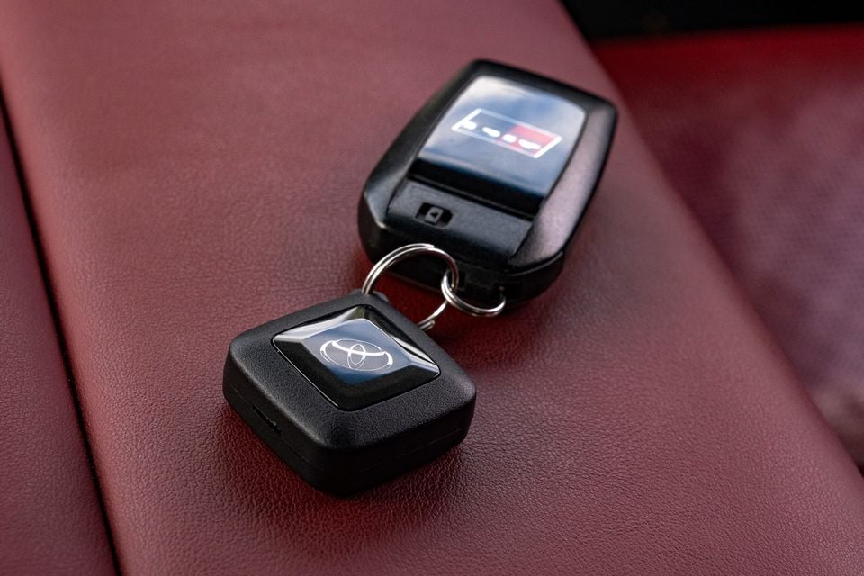 A Toyota key fob and immobiliser tag resting on red leather upholstery inside a car