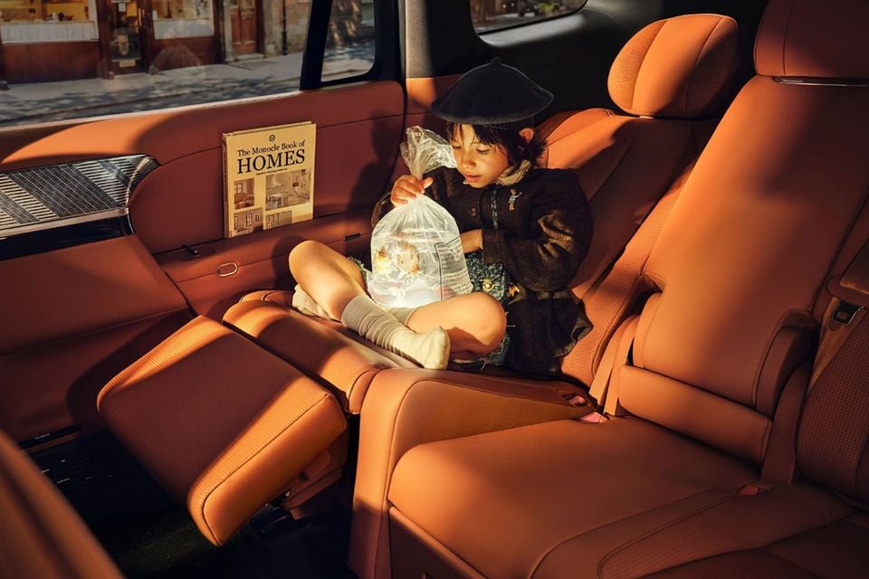 A child sitting in the luxurious tan leather second-row seats of a 2026 Xpeng G9L, holding a bag with goldfish inside