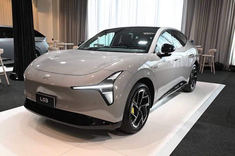 A grey 2026 Xpeng L03 sedan on display at an indoor event, seen from the front-left side