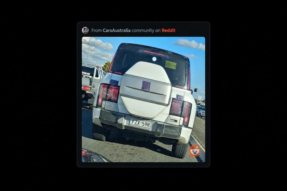 Rear view of a white Yangwang U9 SUV spotted on an Australian road, showing a spare wheel mounted on the tailgate and distinctive tail lights, shared from the CarsAustralia Reddit community.