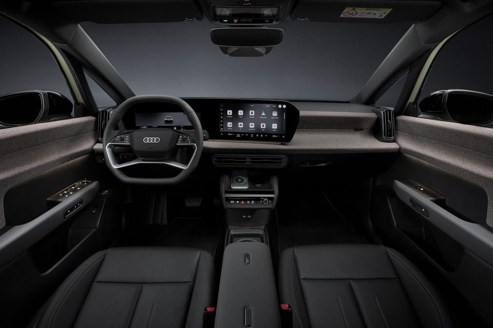Interior of the 2027 Audi A2 e-tron showing the dashboard, wide infotainment touchscreen, digital instrument cluster, steering wheel, and dark leather front seats