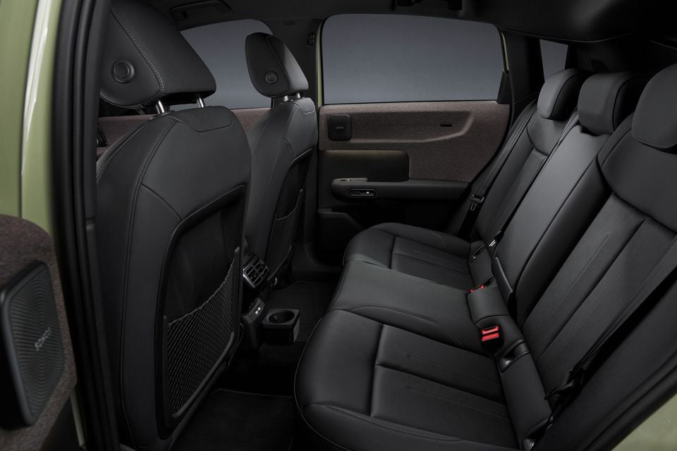 Rear interior of the 2027 Audi A2 e-tron showing black leather rear seats with centre armrest, rear air vents, and a Sonos speaker on the door panel
