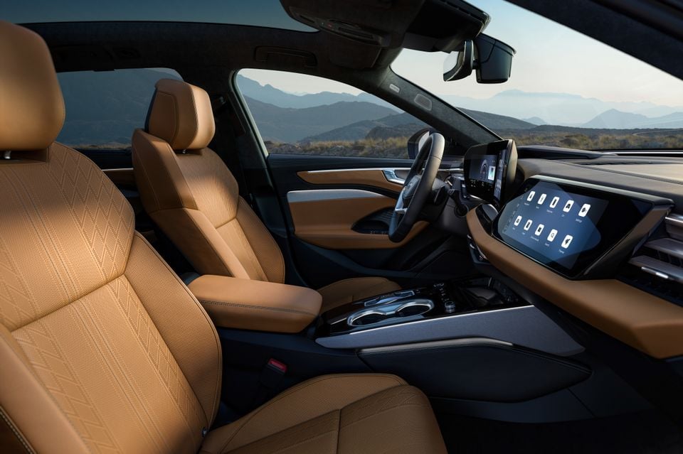 Bancos dianteiros em couro bege, volante e telas curvas de infoentretenimento dentro do Audi A6 Allroad quattro 2027, vistos através da porta do passageiro