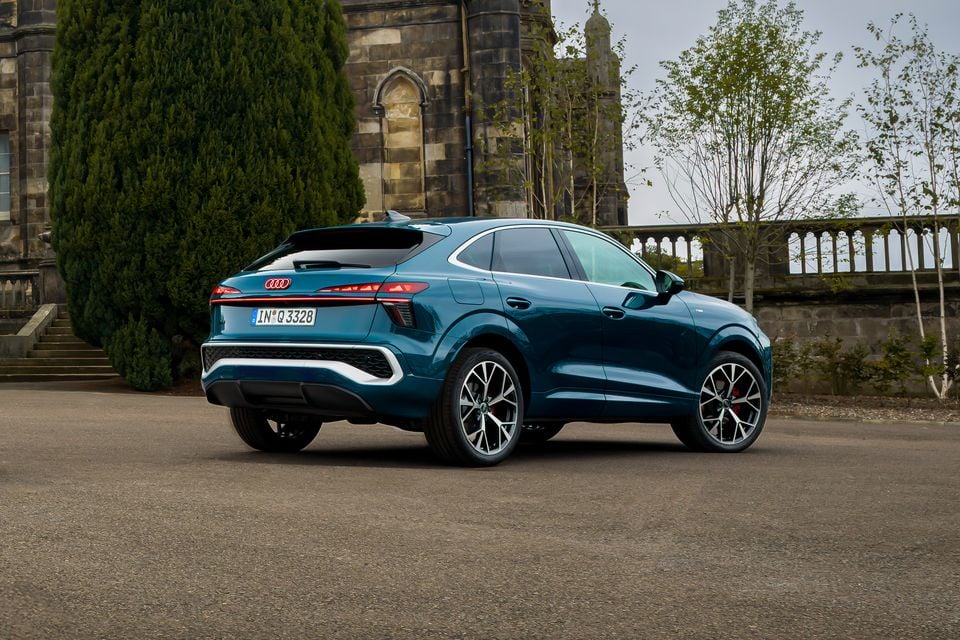 A teal 2027 Audi Q3 Sportback SUV seen from the rear three-quarter angle, parked near a stone building