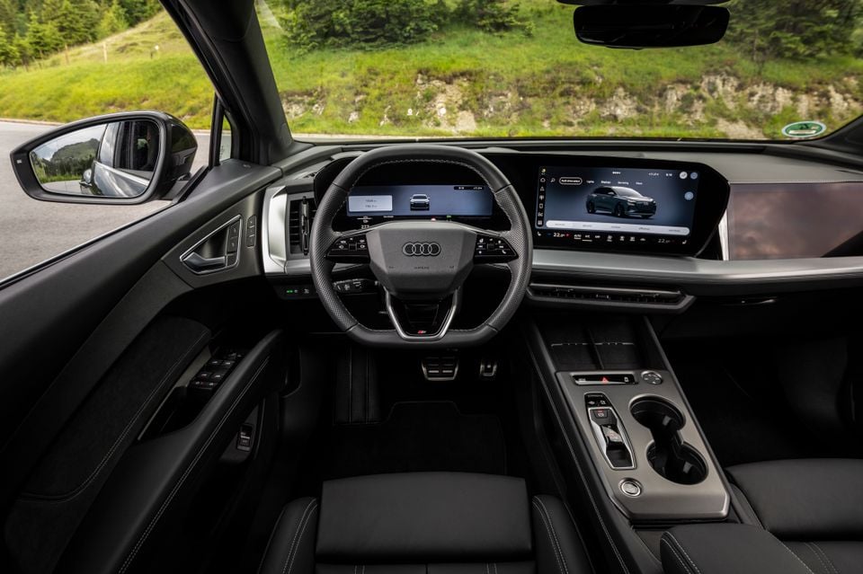 Interior of a 2027 Audi Q4 e-tron showing the steering wheel, panoramic digital display, centre console and dark upholstery
