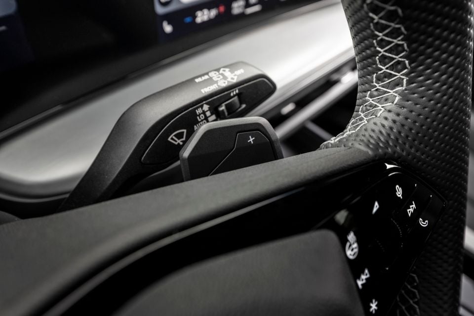 Close-up of the wiper stalk control and part of the steering wheel inside a 2027 Audi Q4 e-tron, showing wiper speed settings and steering wheel buttons