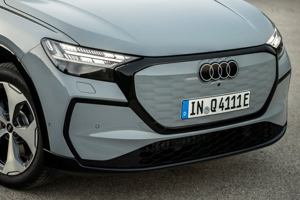 Close-up of the front fascia of a grey Audi Q4 e-tron showing the closed grille, four-ring badge, and LED headlights